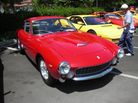 1998 Ford Crown Victoria - Several exotic cars are parked in a lot, including a red vintage Ferrari coupe and a yellow Ferrari.