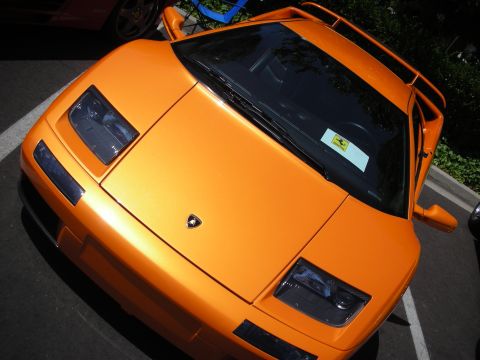 1998 Ford Crown Victoria - A bright orange Lamborghini Diablo is parked, with a yellow sticker on the windshield.