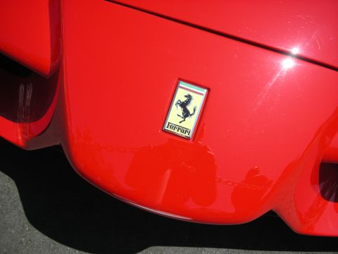 1998 Ford Crown Victoria - The iconic Prancing Horse emblem is clearly visible on the bright red exterior of the vehicle.