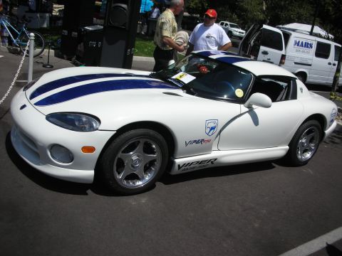 1998 Ford Crown Victoria - A white Dodge Viper with blue racing stripes is parked on asphalt, with people and a van in the background.