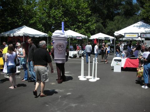 1998 Ford Crown Victoria - A person walks in a coffee cup costume at an outdoor event with tents and people.