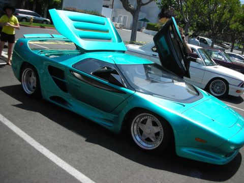 1998 Ford Crown Victoria - Teal Vector W8 Twin Turbo sports car with gullwing doors open at a car show.