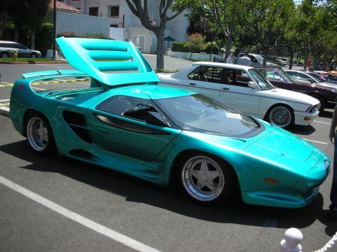 1998 Ford Crown Victoria - A teal sports car is parked in a lot with its engine cover open, showing off its unique design.