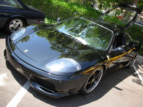 1998 Ford Crown Victoria - A black Ferrari with its doors open is parked next to another vehicle.