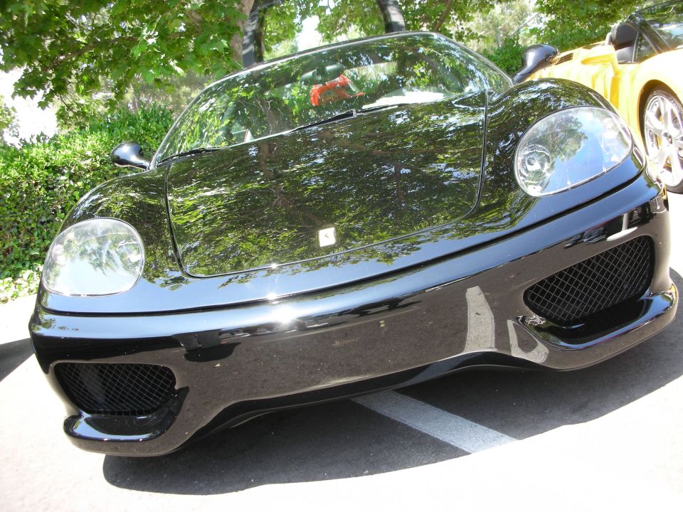 Black sports car front view with yellow car in background