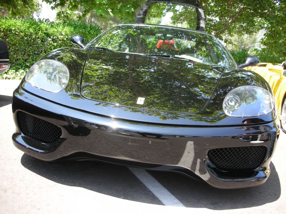 Black Ferrari 360 Modena front view, yellow car partially visible to the right