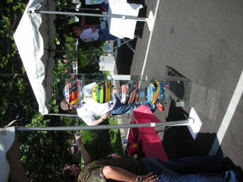 1998 Ford Crown Victoria - A collection of colorful racing helmets is displayed outdoors under a tent, with spectators observing.