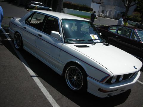 1998 Ford Crown Victoria - White BMW sedan with M stripes parked in a lot, another car is visible to the right.