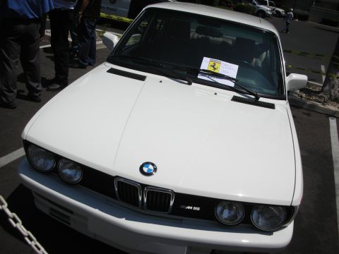 1998 Ford Crown Victoria - A white BMW M5 is parked in a lot, with a Ferrari sticker on its windshield.