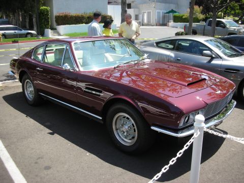 1998 Ford Crown Victoria - A maroon coupe with a distinctive hood scoop is parked in a lot next to a modern silver car.