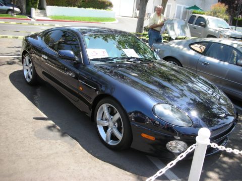 1998 Ford Crown Victoria - A dark blue coupe is parked in front of a silver car, with a man standing near a pickup truck.