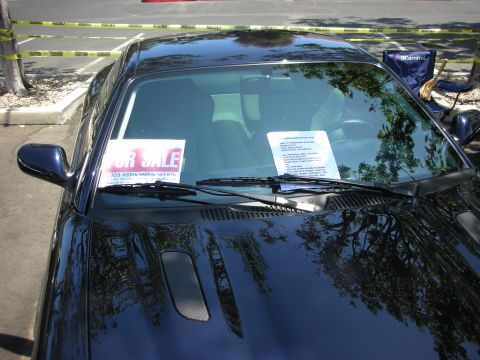 1998 Ford Crown Victoria - A dark coupe is parked outdoors with a "FOR SALE" sign and a detailed information sheet on its windshield.