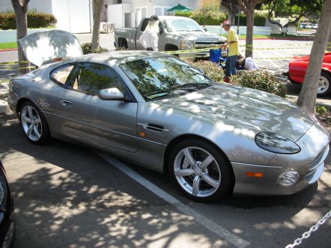 1998 Ford Crown Victoria - A silver coupe is parked with its hood open, alongside other vehicles at an outdoor gathering.