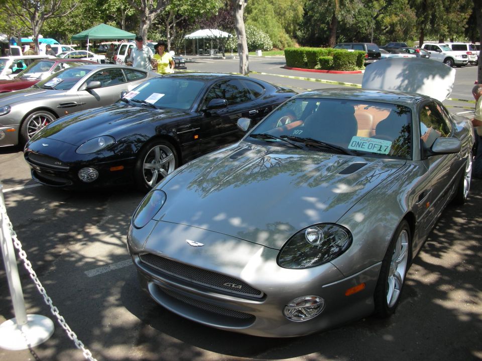 Silver Aston Martin DB7 with a black Aston Martin DB7 behind it. License plate reads 'ONE OF 17'
