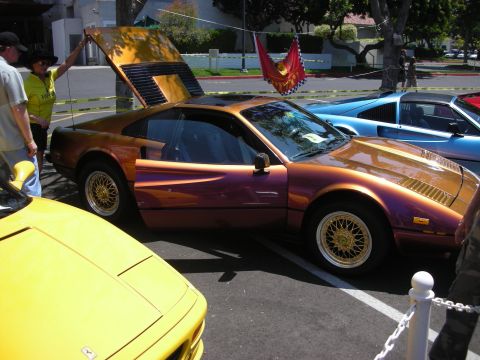 1998 Ford Crown Victoria - A custom-painted Ferrari 308 GTB is displayed at an outdoor event with other vehicles.