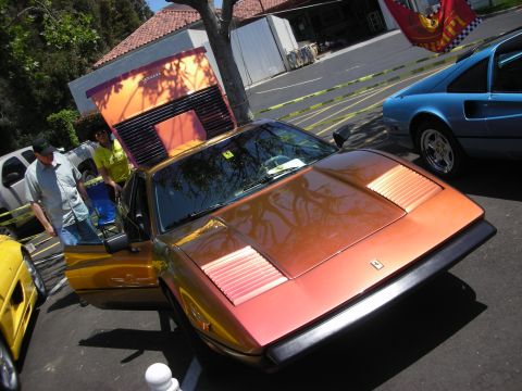 1998 Ford Crown Victoria - An orange Ferrari is displayed with its hood open, while a blue Ferrari is parked next to it at an outdoor event.