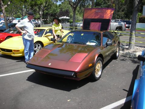 1998 Ford Crown Victoria - A metallic brown Ferrari 308 GTB is parked at an outdoor event with its engine cover raised.