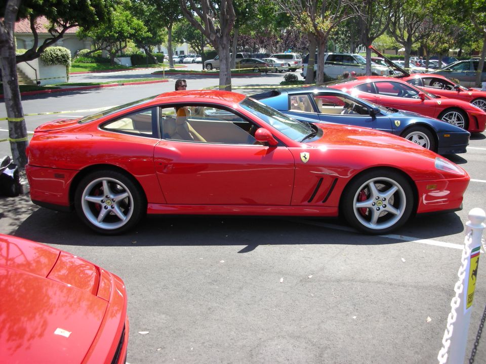 Red sports car, side view, tan interior, five-spoke wheels, parked in lot