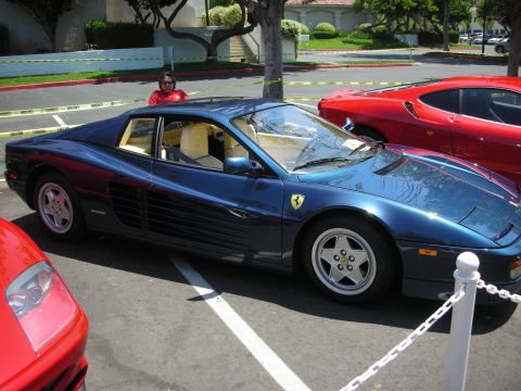 1998 Ford Crown Victoria - A blue Ferrari Testarossa is parked in a lot, with other red sports cars visible nearby.