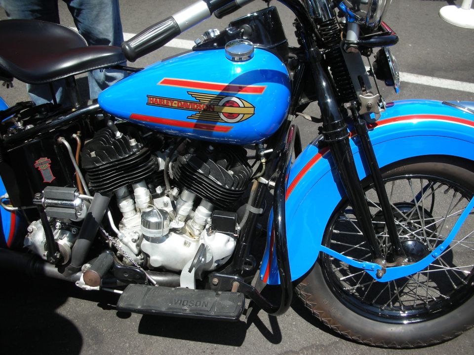 Blue Harley-Davidson motorcycle with red stripes, showing the engine and front wheel