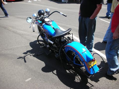 1998 Ford Crown Victoria - A vintage blue motorcycle is parked on asphalt, with several people standing nearby.