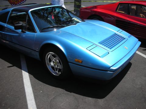 1998 Ford Crown Victoria - A blue sports car is parked next to a red car at an outdoor event.
