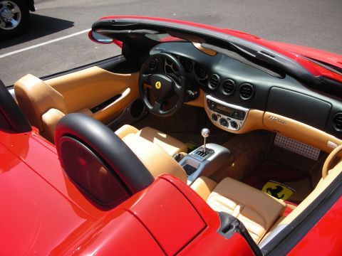 1998 Ford Crown Victoria - The interior of a red convertible shows tan leather seats and a black dashboard with a Ferrari emblem on the steering wheel.