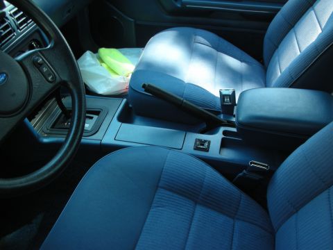 1998 Ford Crown Victoria - Interior view of a car with blue seats and a center console. A plastic bag sits on the passenger seat.