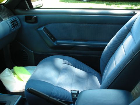 1998 Ford Crown Victoria - Interior view of a blue car seat and door panel, showing the handbrake and air vent.