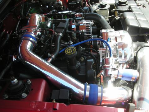 1998 Ford Crown Victoria - Close-up view of a modified engine bay a polished supercharger and custom intake plumbing.