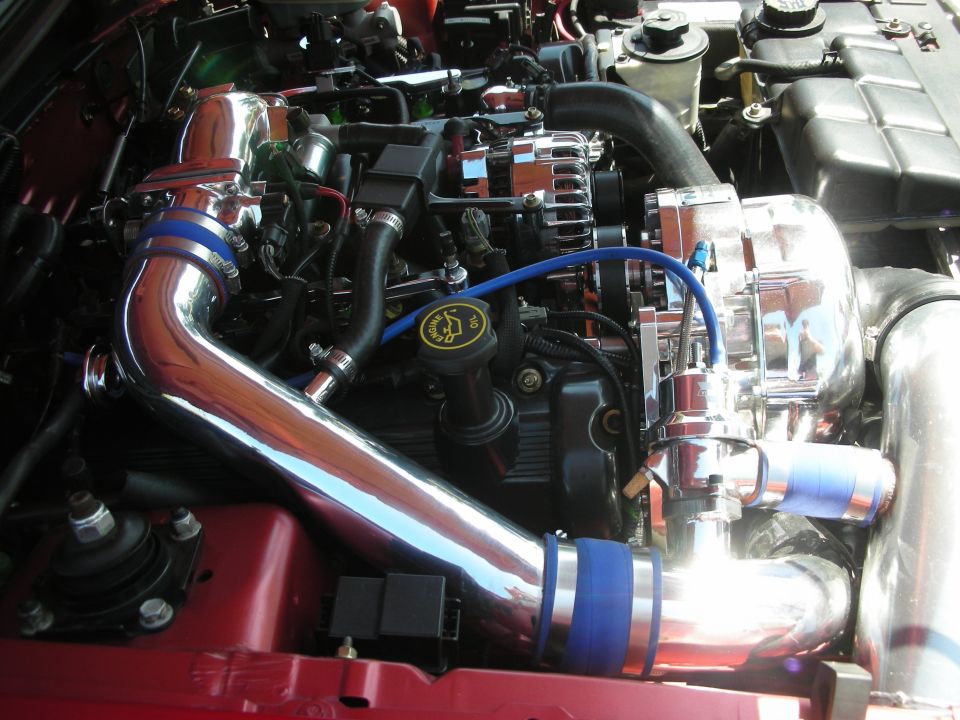 Engine bay with chrome supercharger, intake piping, and blue hose accents