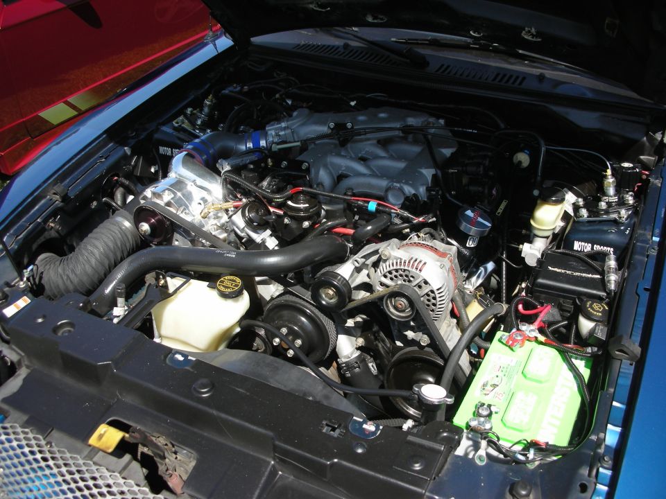 Engine bay with supercharger, intake, alternator, and battery