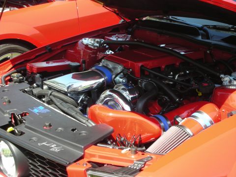 1998 Ford Crown Victoria - The engine bay of a car features a turbocharger and custom intake system, with another vehicle partially visible.