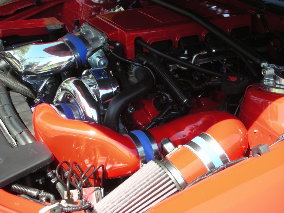 Engine bay with chrome turbocharger, red intake manifold, and orange piping