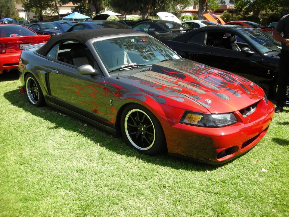 Red and grey convertible Mustang with flame decals, front 3/4 view