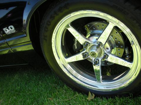 1998 Ford Crown Victoria - A close-up view of a custom wheel and tire assembly on a black vehicle, a '5.0 Mustang' emblem.