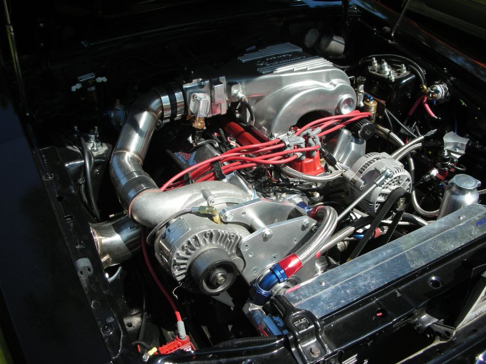 Engine bay with a polished intake manifold, red spark plug wires, and a turbocharger. The engine is black with chrome accents