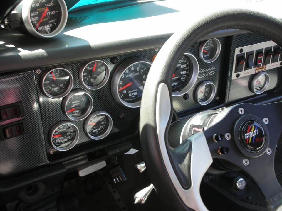 Dashboard with numerous gauges including RPM, MPH, oil pressure, fuel level, water temperature, and brake pressure. Grant steering wheel visible