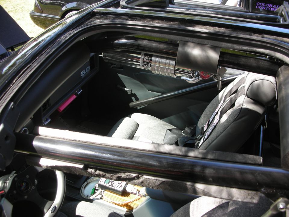 Interior of a modified car with racing seats, roll cage, and a "5.0" badge