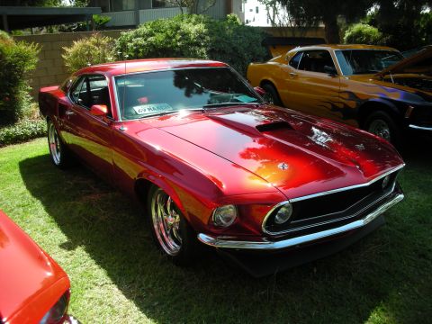 1998 Ford Crown Victoria - Red 1969 Ford Mustang parked on grass, with another Mustang in the background.