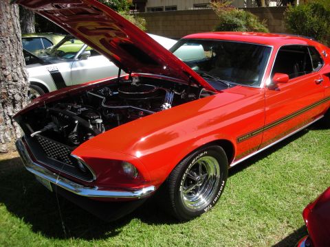 1998 Ford Crown Victoria - A red 1969 Ford Mustang Mach 1 is displayed with its hood open, revealing the engine bay.