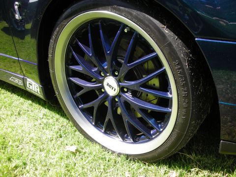 1998 Ford Crown Victoria - A customized car wheel with a unique spoke design and a prominent tire size marking is shown parked on grass.