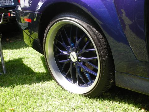 1998 Ford Crown Victoria - Close-up of a custom wheel and tire on a purple vehicle, with a partial license plate visible in the background.