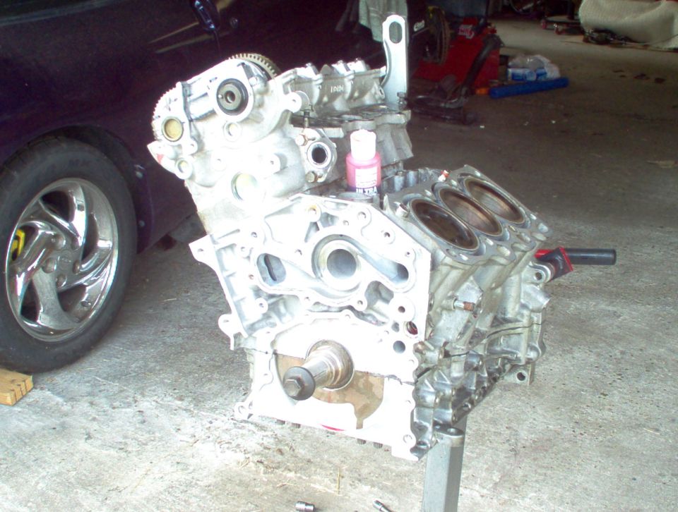 Engine block on stand next to purple car wheel