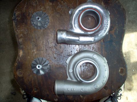 1996 Ford Probe - Two turbocharger housings and two turbine wheels are laid out on a rustic wooden surface.