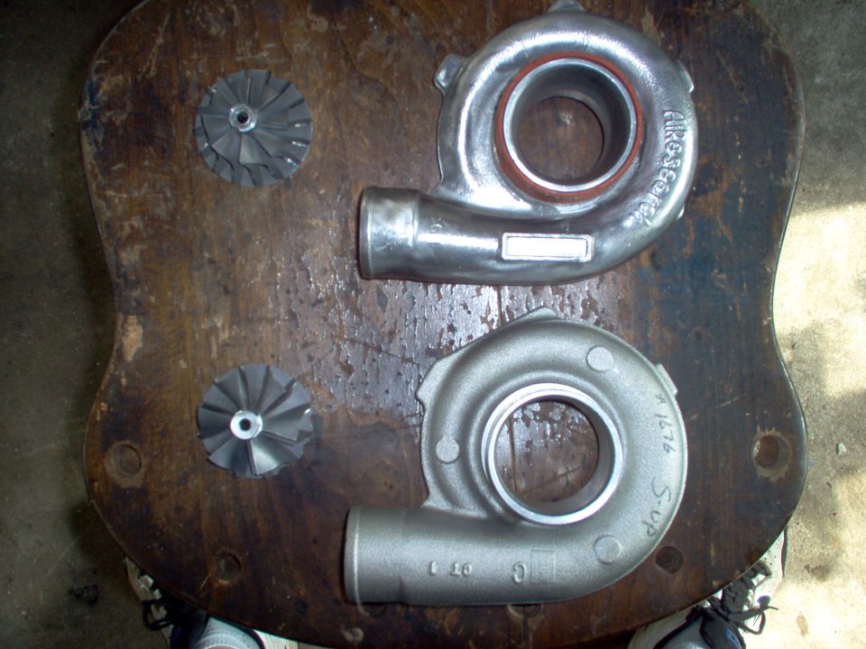 Two turbocharger housings and two turbine wheels on a wooden table