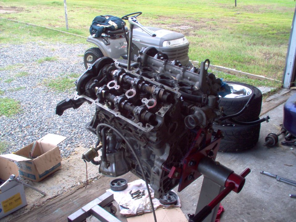 Engine on a red and silver stand, with a lawn tractor in the background