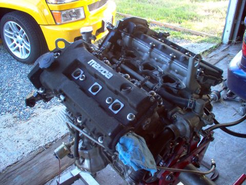 1996 Ford Probe - Mazda engine on a stand, with a yellow truck partially visible in the background.