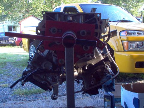 1996 Ford Probe - Engine on a stand in front of a yellow truck.