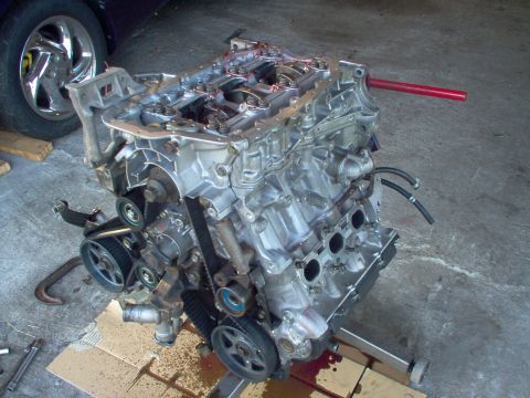 1996 Ford Probe - A V6 engine is shown on an engine stand, with a car's chrome wheel in the background.